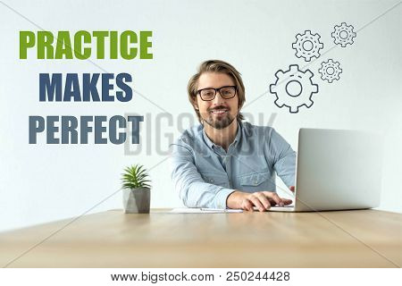 Smiling Businessman Working At Laptop In Office With Practice Makes Perfect Inscription And Cogs Ico