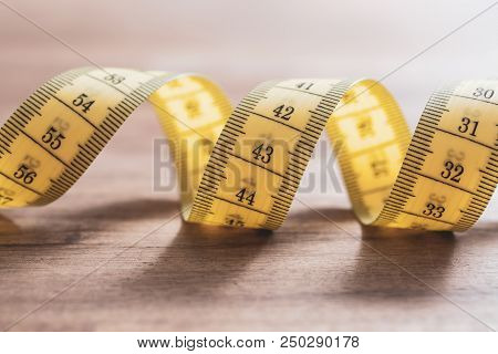 A Soft Yellow Measuring Tape In Spiral Shape On A Table