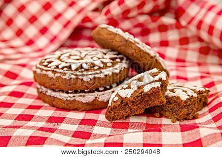 Pile Of Gingerbread Cookies With Two Broken Pieces On Red And White Tradational Tablecloth