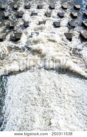 Top Perspective View To Flow Of Foaming Water Crashing On Small Trapezium Concrete Stones-breakwater
