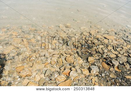 Stony Shore Of The Lake With Clear And Transparent Water