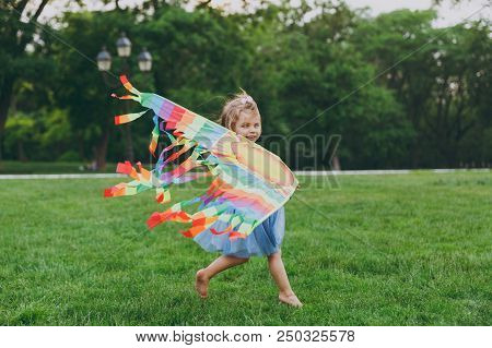 Joyful Little Cute Child Baby Girl In Denim Dress Running, Play With Colorful Kite And Have Fun In G