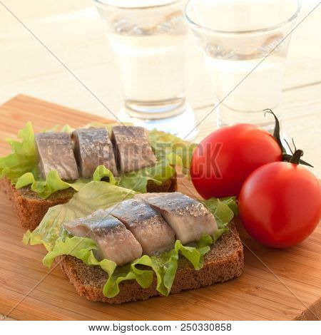 Two Sandwiches Of Rye Bread And Herring With Lettuce And Tomatoes