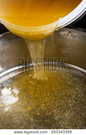 Strain The Poured Honey Through A Sieve. How To Harvest Honey. Filtering Raw Honey.