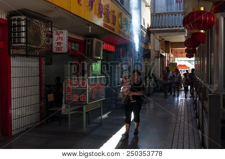 Dunhuang, China - August 7, 2012: Street Scene In The City Of Dunhuang, With A Woman Carrying A Baby
