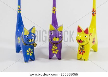 Perspective Front Shot Of Blue, Yellow And Purple Cat Figures Of Wooden Carved Nicknack