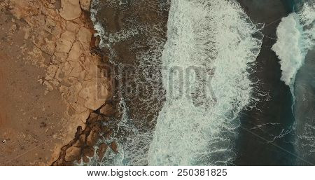Aerial Photography. The Sea Wave Covered The Stone Shore. On The Sea Rose Strong Waves.