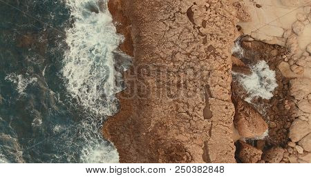 Aerial Photography.stone Cliff. Waves Beat Against The Rocks. Foam Waves. One Wave Rolls On The Othe
