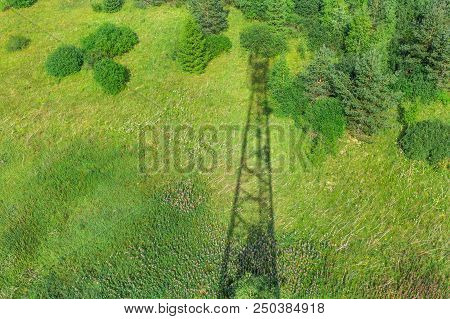 Shadow Of Telecommunication Tower With Radio Antennas And Satellite Dishes On The Green Field With G