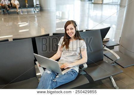 Young Pretty Traveler Tourist Woman With Headphones Listening Music Working On Laptop, Wait In Lobby