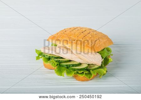 Pressed And Toasted Double Panini With Ham And Cheese Served On Sandwich Paper On A Wooden Table