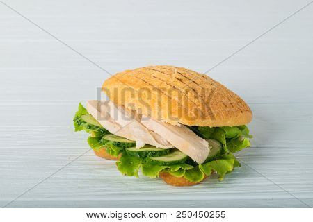 Pressed And Toasted Double Panini With Ham And Cheese Served On Sandwich Paper On A Wooden Table