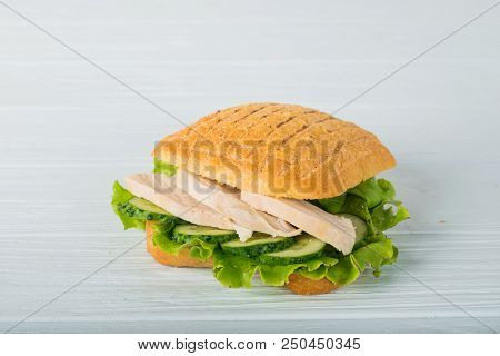 Pressed And Toasted Double Panini With Ham And Cheese Served On Sandwich Paper On A Wooden Table
