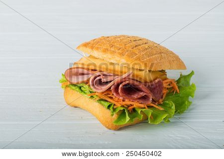 Pressed And Toasted Double Panini With Ham And Cheese Served On Sandwich Paper On A Wooden Table