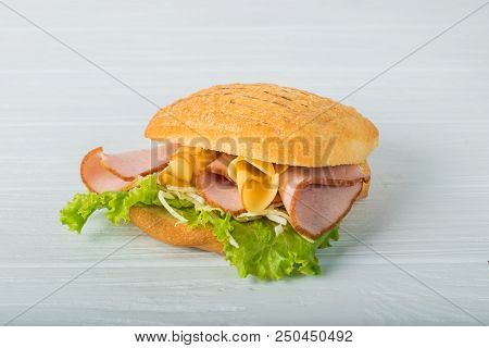 Pressed And Toasted Double Panini With Ham And Cheese Served On Sandwich Paper On A Wooden Table