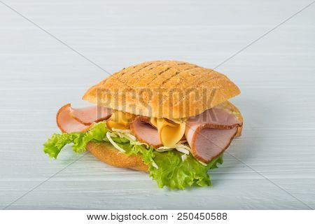 Pressed And Toasted Double Panini With Ham And Cheese Served On Sandwich Paper On A Wooden Table