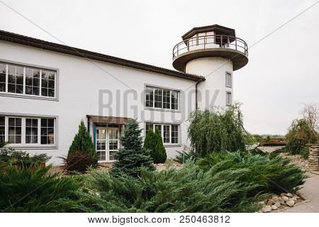 The Building Of The Lighthouse On The Shore Is Buried In Greenery. Lighthouse At Sea