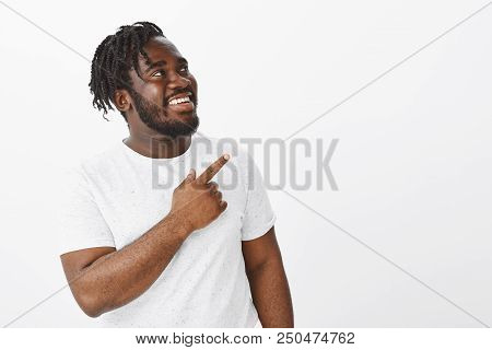 Portrait Of Positive Happy Dark-skinned Fat Male Model With Beard, Looking And Pointing At Upper Rig