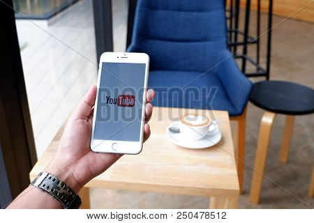 A Man Sit In Cafe Holding Mobile With Youtube Screen