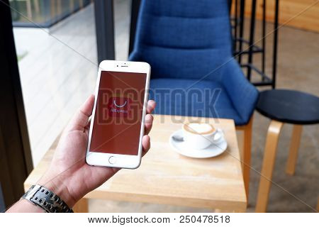 A Man Sit In Cafe Holding Mobile With Aliexpress Screen
