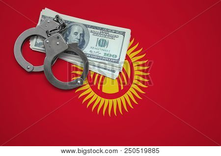 Kyrgyzstan Flag  With Handcuffs And A Bundle Of Dollars. The Concept Of Breaking The Law And Thieves