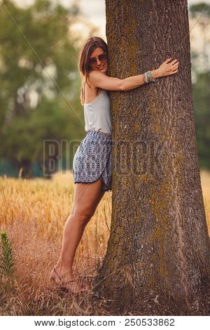 Cute Smiley Girl Embracing The Oak Tree In Nature.