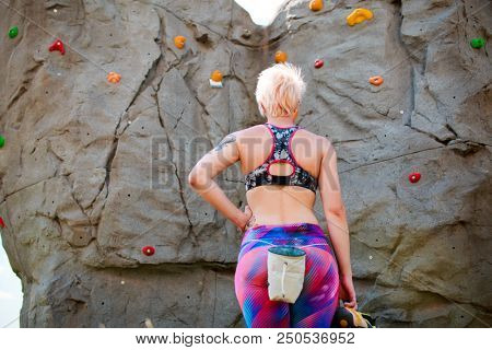 Photo from back of sports woman with bag against rock boulder