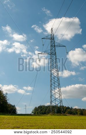 High Voltage Lines And Power Pylons Innatural Landscape On Blue Sky With Puffy Clouds, Cology Concep