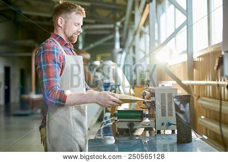Side View Portrait  Of Man Wearing Apron Packing Freshly Roasted Coffee Beans In Craft Paper Bags Wh