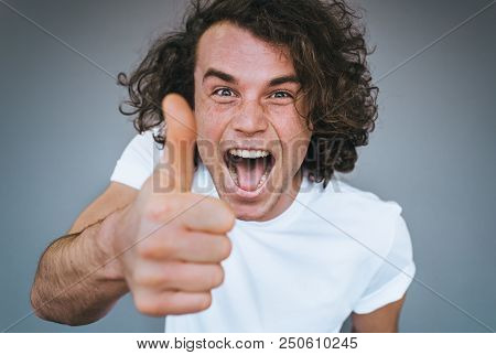 Closeup Shot Of Handsome Male Smling With Healthy Toothy Smile, Wears White T-shirt Looking At The C