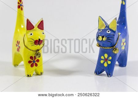 Close-up Front Shot Of Blue And Yellow Small Cat Figures Of Wooden Carved Nicknack