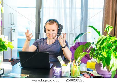 Emotional Man In Headphones Looking At Computer Screen, Gestures And Participating In Online Meeting