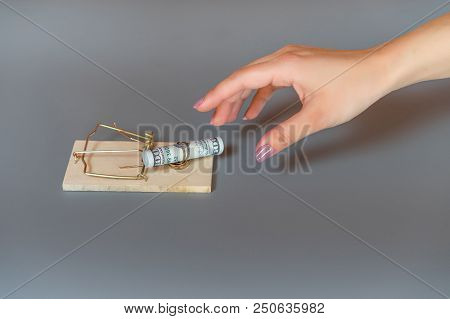 Concept. Hand Reaches For The Mousetrap In Which The Dollars Lie