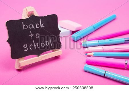 Small Blackboard With Back To School Words And School Supplies Of Bright Pink And Blue Colors On A P