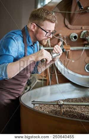 Side View Portrait Of Modern Young Man Wearing Apron And Glasses  Taking Scoop Of Coffee Beans From 