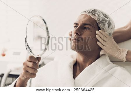 Young Handsome Man In Robe Loking Into Mirror. Smiling Man. Man In White Bathrobe. Anti-aging Cosmet