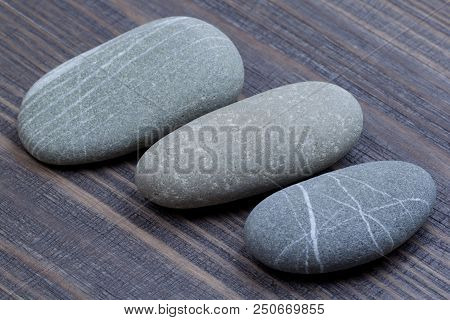 Three Oval Pellets On A Wooden Surface