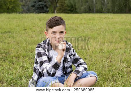 Full-length Portrait Of Attractive Teenage Boy Thinking About Something And Chewing Blade Of Grass. 