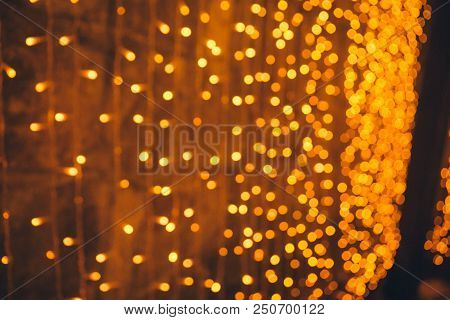 Many Blurred Small Electric Bulbs On A Wall. Yellow Blurred Lights. Wall Of Christmas Lights