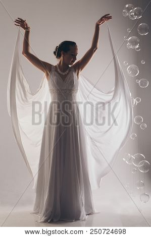 Girl In White And With Raised Hands, Attached To The Floor Dresses. The Bride In A Dress In Greek St