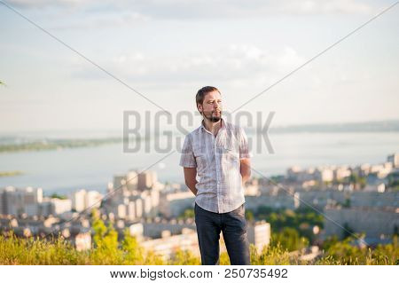 Portrait Of A Man In The Background Of Saratov, Russia, View Of The Houses, The Volga River, The Bri