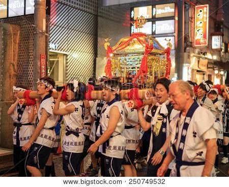 Osaka, Japan - July 23, 2018: Young Men Enthusiastically Carry Small Portable Shrine Through Streets