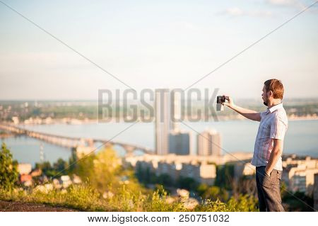 A Man In A Shirt And Trousers Takes Pictures Of Himself And Nature On The Phone. Portrait Of A Man I