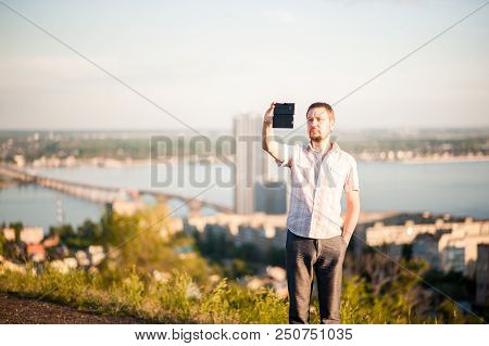 A Man In A Shirt And Trousers Takes Pictures Of Himself And Nature On The Phone. Portrait Of A Man I