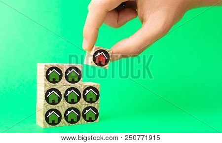 The Businessman's Hand And Wooden Cubes With Houses. Investment In Real Estate. Buildin, Sale, Rent,