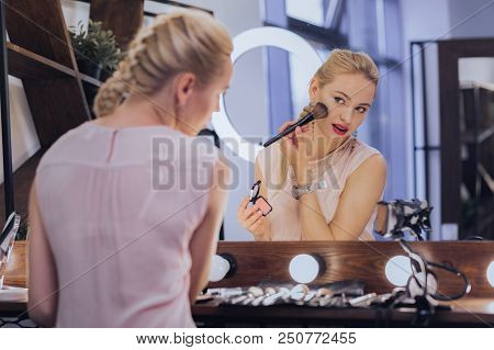 Fishbone Braid. Blonde-haired Woman With Fishbone Braid Putting Makeup On While Sitting Near Big Lig