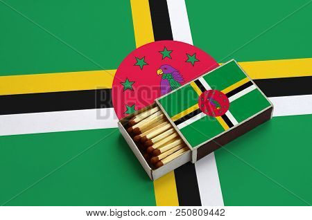 Dominica Flag  Is Shown In An Open Matchbox, Which Is Filled With Matches And Lies On A Large Flag.
