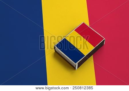 Chad Flag  Is Pictured On A Matchbox That Lies On A Large Flag.