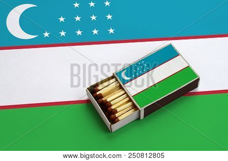Uzbekistan Flag  Is Shown In An Open Matchbox, Which Is Filled With Matches And Lies On A Large Flag