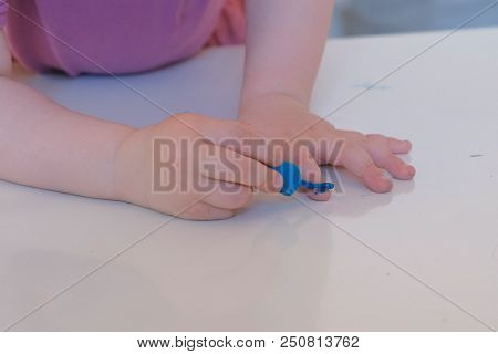Little Cute Girl Paints Her Nails With Blue Varnish.